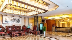 A lobby with ornate wooden furniture, a large chandelier, and a reception desk. - Xikelai Hotel (Qingdao)
