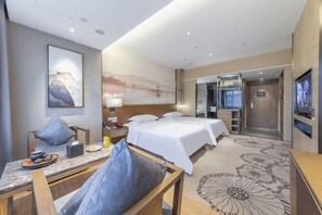 Een hotelkamer met een bed, een bureau, een stoel, een televisie en een schilderij aan de muur.