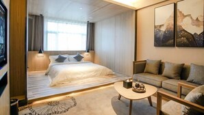 Une chambre d’hôtel moderne, équipée d’un lit, d’un canapé, d’une table basse et ornée d’œuvres d’art sur les murs.