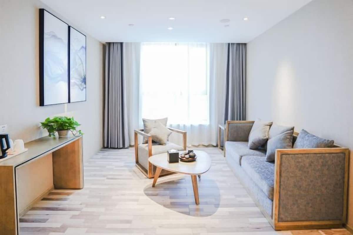 Ein modernes Wohnzimmer mit einer Couch, einem Couchtisch und einem Schreibtisch mit Pflanze.
