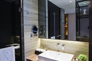 A modern bathroom with a large mirror, a white sink, and a glass shower enclosure.