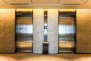 Un ascensor moderno con puertas metálicas y suelo de mármol.