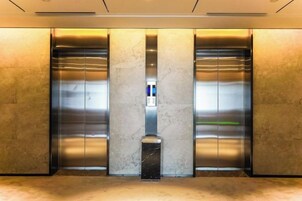 Un ascensor moderno con puertas metálicas y suelo de mármol.