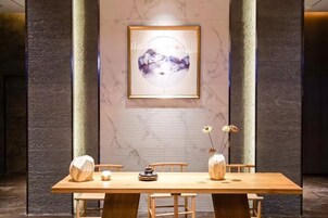 A dining area with a long wooden table, chairs, and a vase with flowers.