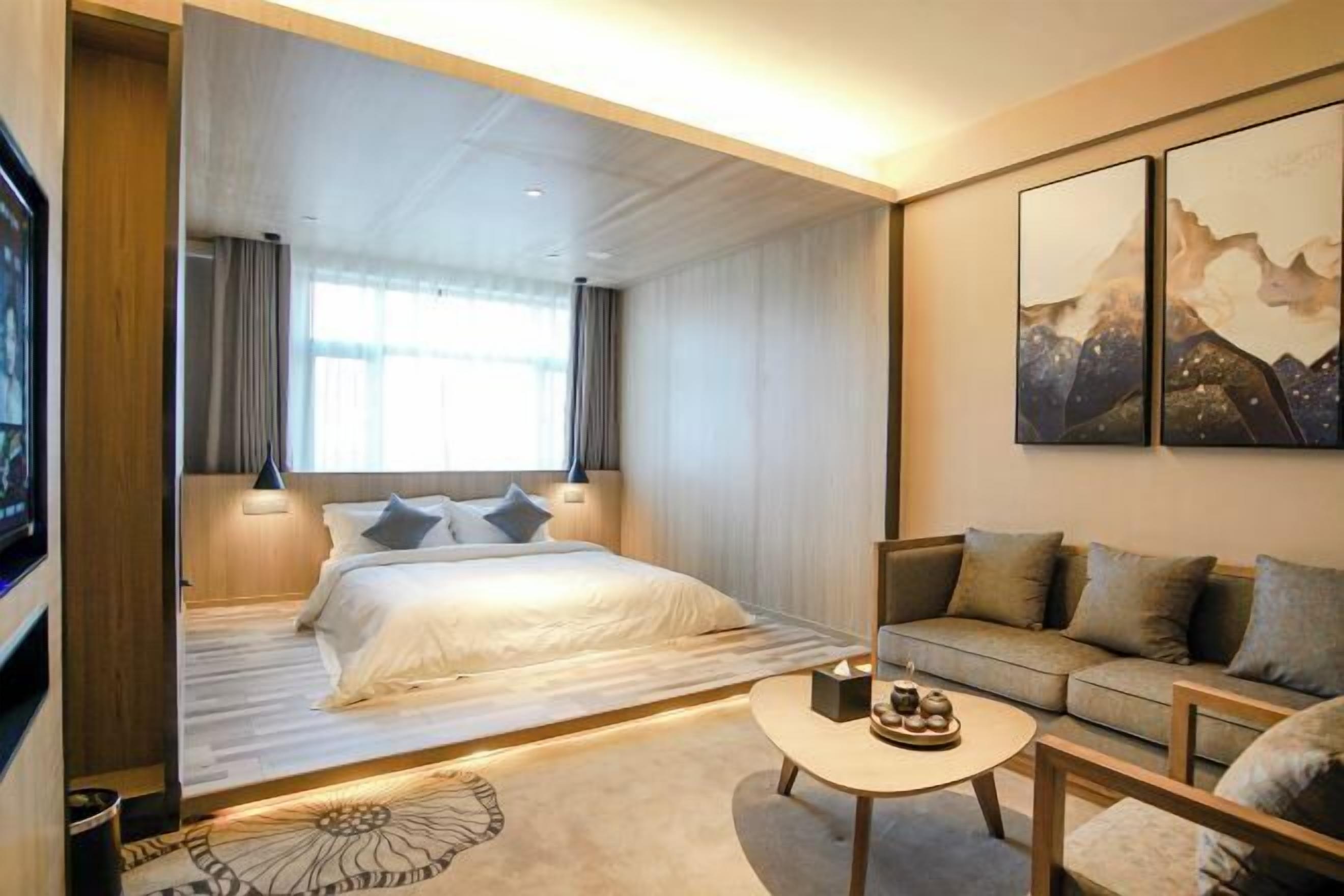 Una habitación de hotel moderna con una cama, un sofá, una mesa de centro y obras de arte en la pared.
