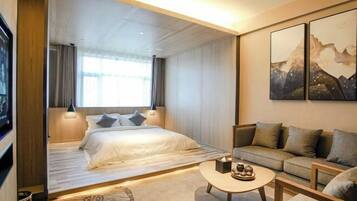Una habitación de hotel moderna con una cama, un sofá, una mesa de centro y obras de arte en la pared.