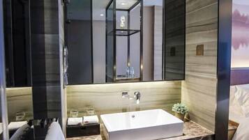 Un baño moderno con un espejo grande, un lavamanos rectangular y una zona de ducha.