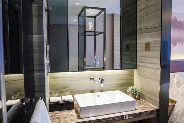 A modern bathroom with a large mirror, a rectangular sink, and a shower area.
