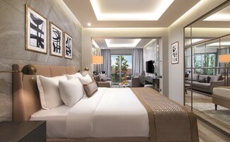 Habitación de hotel moderna con una cama grande, un escritorio, un sofá y un balcón con vistas.