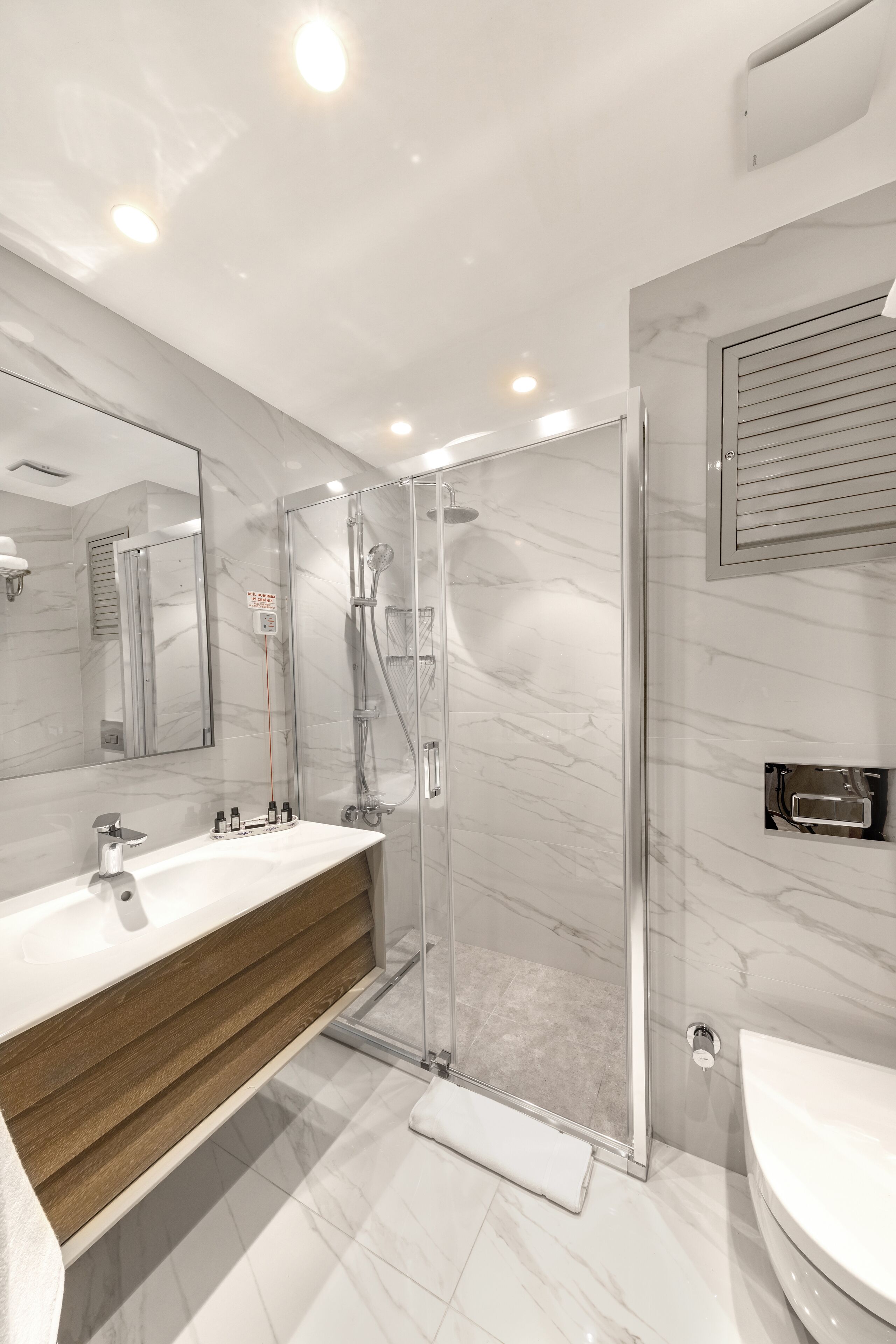 Une salle de bain moderne avec un meuble-lavabo en marbre, une douche à parois de verre et des toilettes.