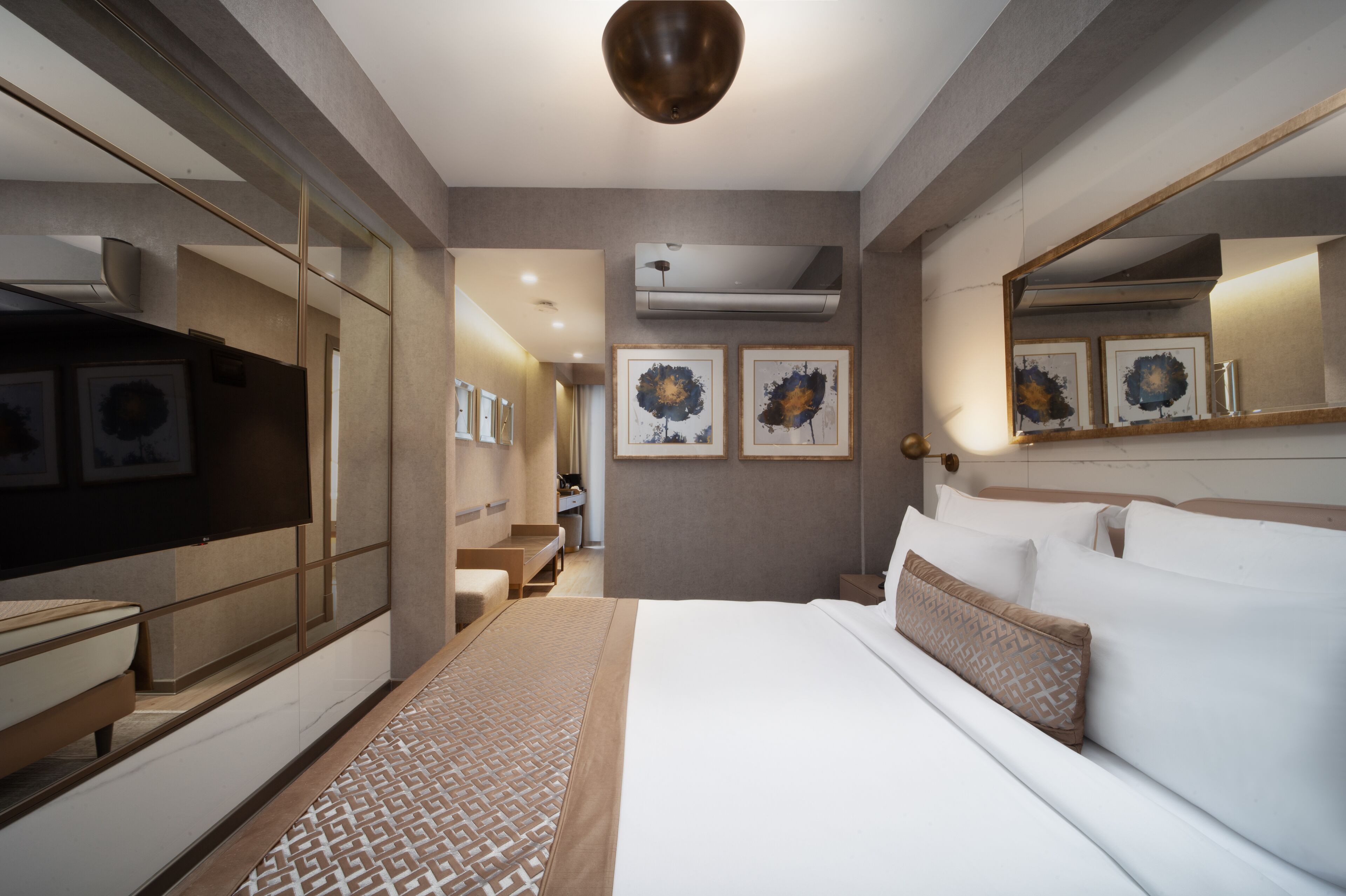 Una habitación de hotel moderna con una cama grande, una mesita de noche, un espejo y obras de arte en las paredes.