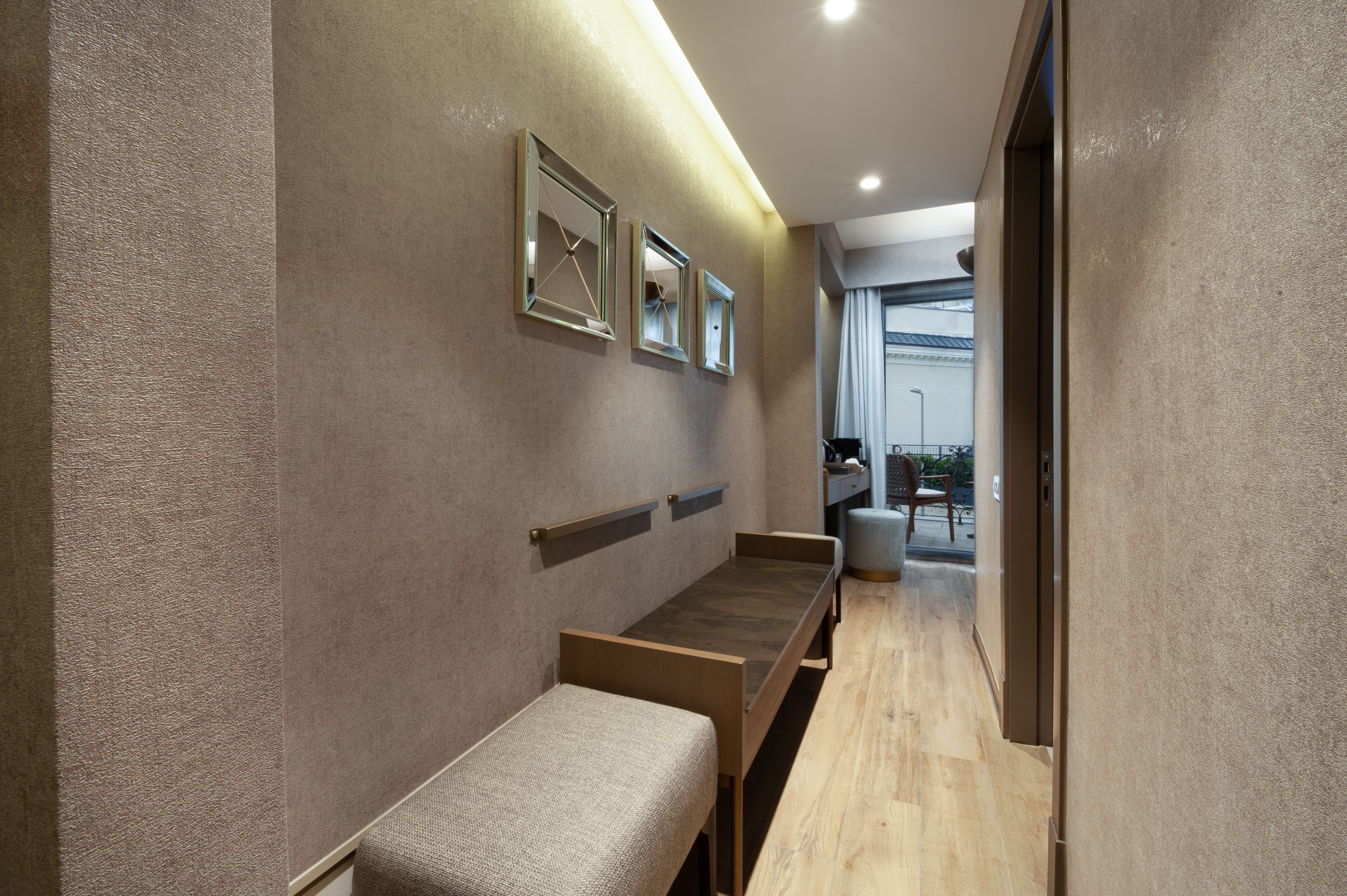 A hallway with a bench, a wall-mounted mirror, and a door leading to a balcony.