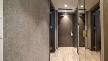 Un couloir avec un mur à texture, un plancher en bois et une porte dotée d’un porte-serviettes.