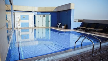Una piscina al aire libre, sillones reclinables de piscina