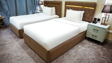 A hotel room with two beds, a nightstand with a lamp, and a patterned carpet.