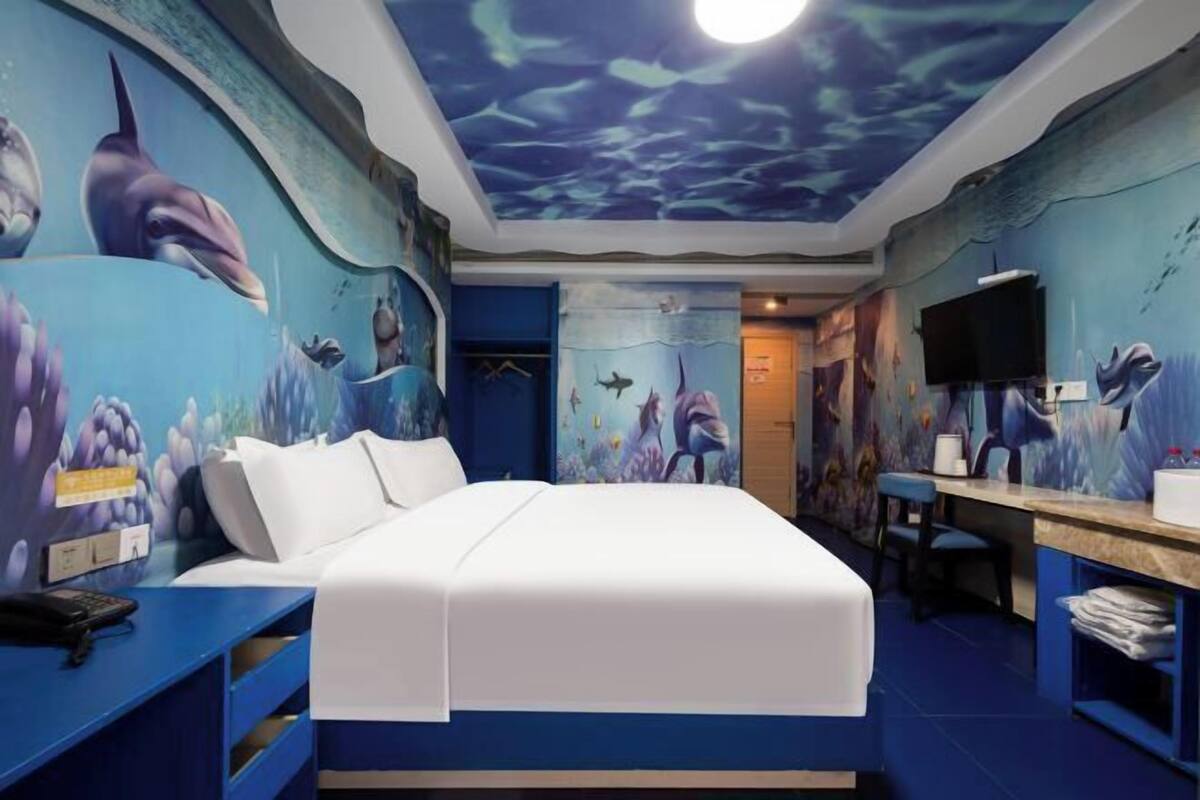 Una habitación con un mural al estilo submarino, una cama, un escritorio y un televisor.