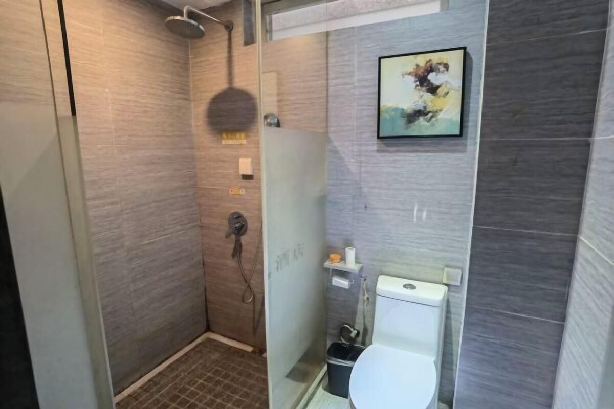 Une salle de bain moderne avec une douche à parois de verre, des toilettes et une petite étagère contenant des articles de toilette.