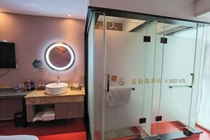 Une salle de bain moderne avec un miroir rond, un lavabo et une cabine de douche en verre.