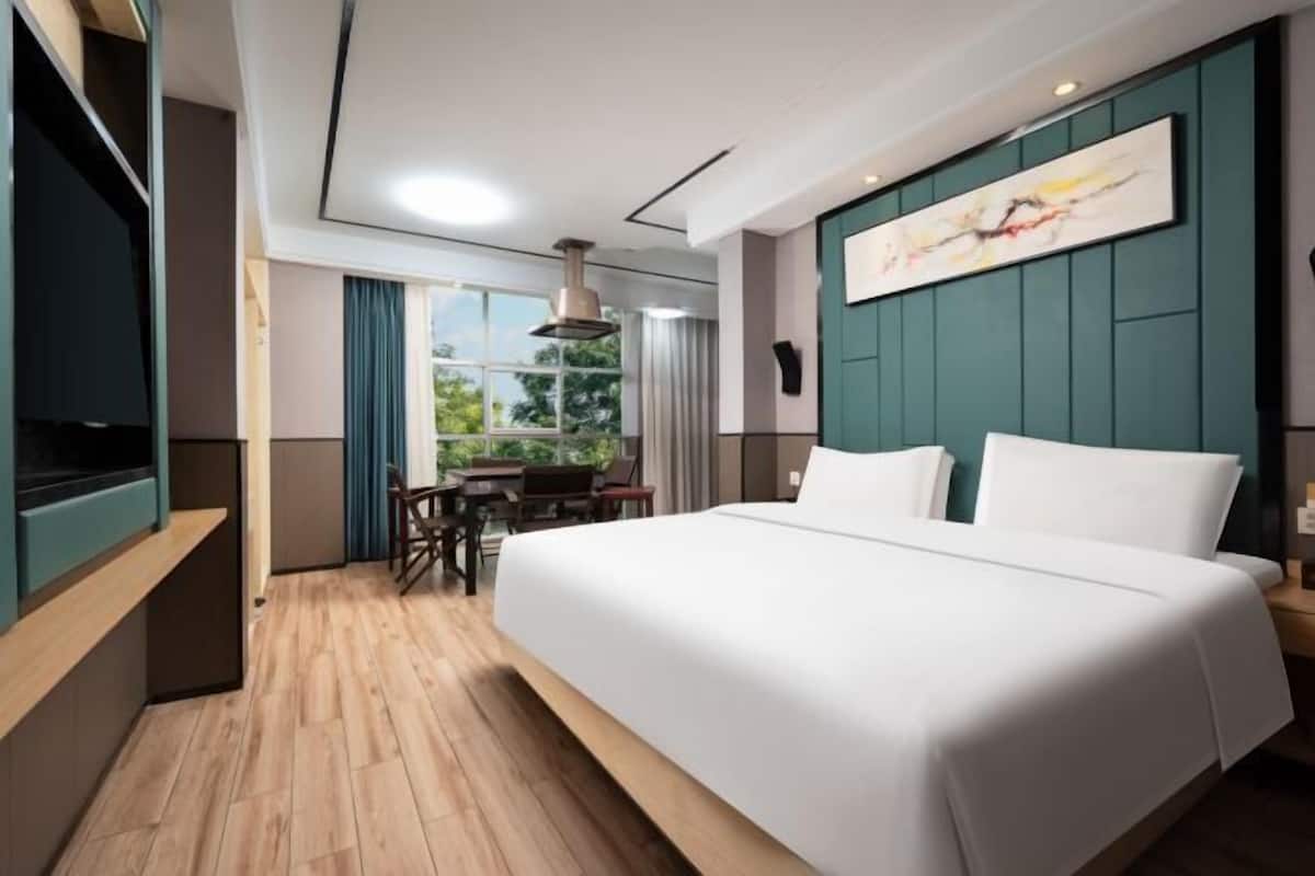 Una habitación de hotel con una cama grande, una mesa de comedor y un televisor.