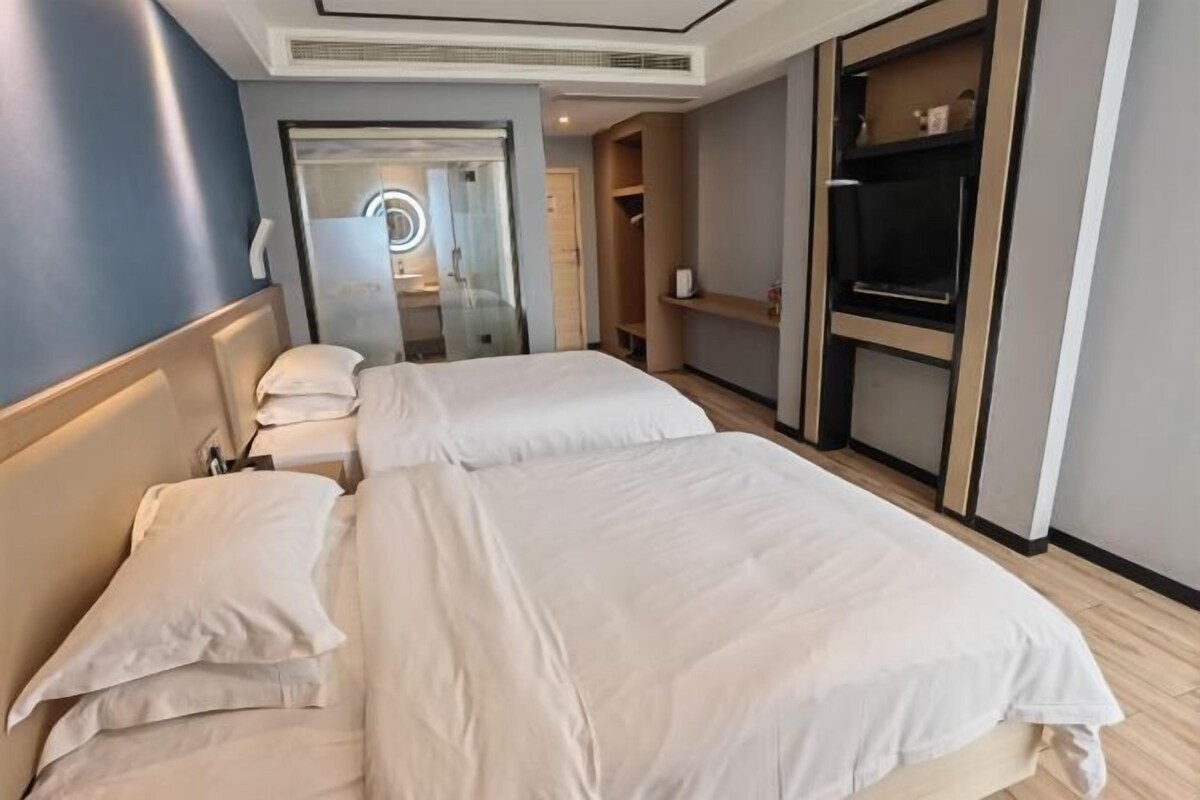 Une chambre d’hôtel avec deux lits, un dressing et un miroir avec éclairage.