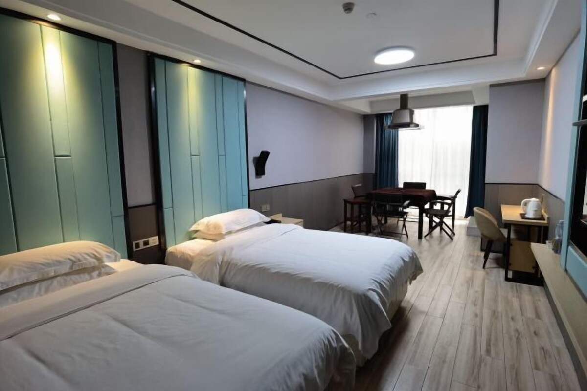 Une chambre d’hôtel avec deux lits, un bureau et une chaise.