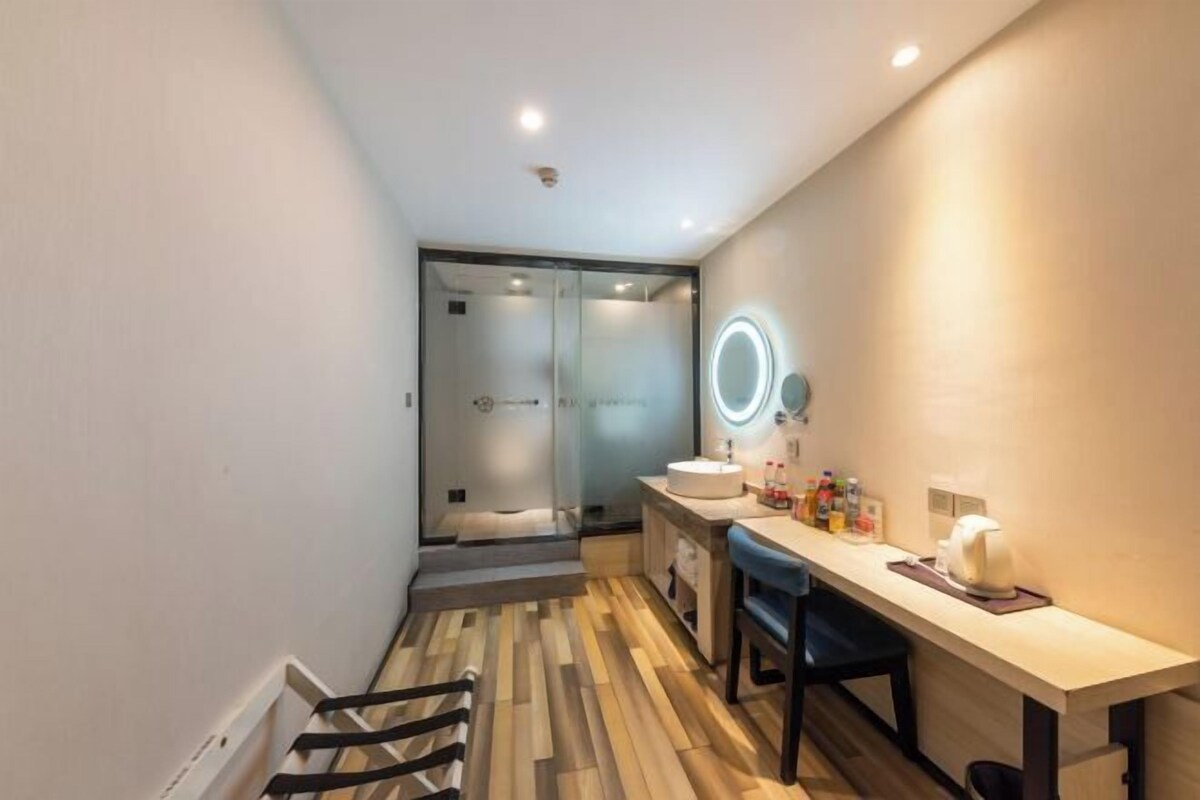 Une salle de bain moderne avec une douche à parois de verre, un meuble-lavabo avec un miroir et un plancher en bois.