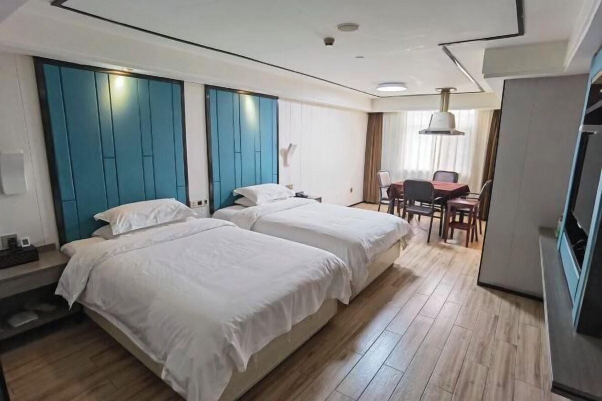 Une chambre d’hôtel avec deux lits, un bureau et une chaise.