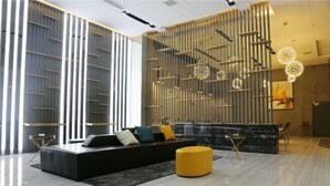 A modern interior with a black sofa, yellow ottoman, and a black marble reception desk. - Mi Boutique Chain Hotel Xiantao (Xiantao)