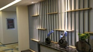 A reception area with a modern design, featuring a reception desk, vertical wooden slats, and decorative vases. - Mi Boutique Chain Hotel Xiantao (Xiantao)
