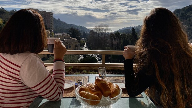 Dos personas sentadas en una mesa con vistas a un valle y edificios.