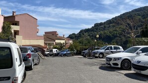 Un estacionamiento con varios coches, incluyendo una furgoneta blanca y un Mercedes-Benz blanco.