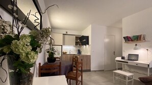 Un espacio habitable compacto con comedor, pequeña cocina y área de trabajo.