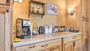 Una cocina con armarios de madera, un letrero que dice 'cafetería', una cafetera y diversos utensilios de cocina.