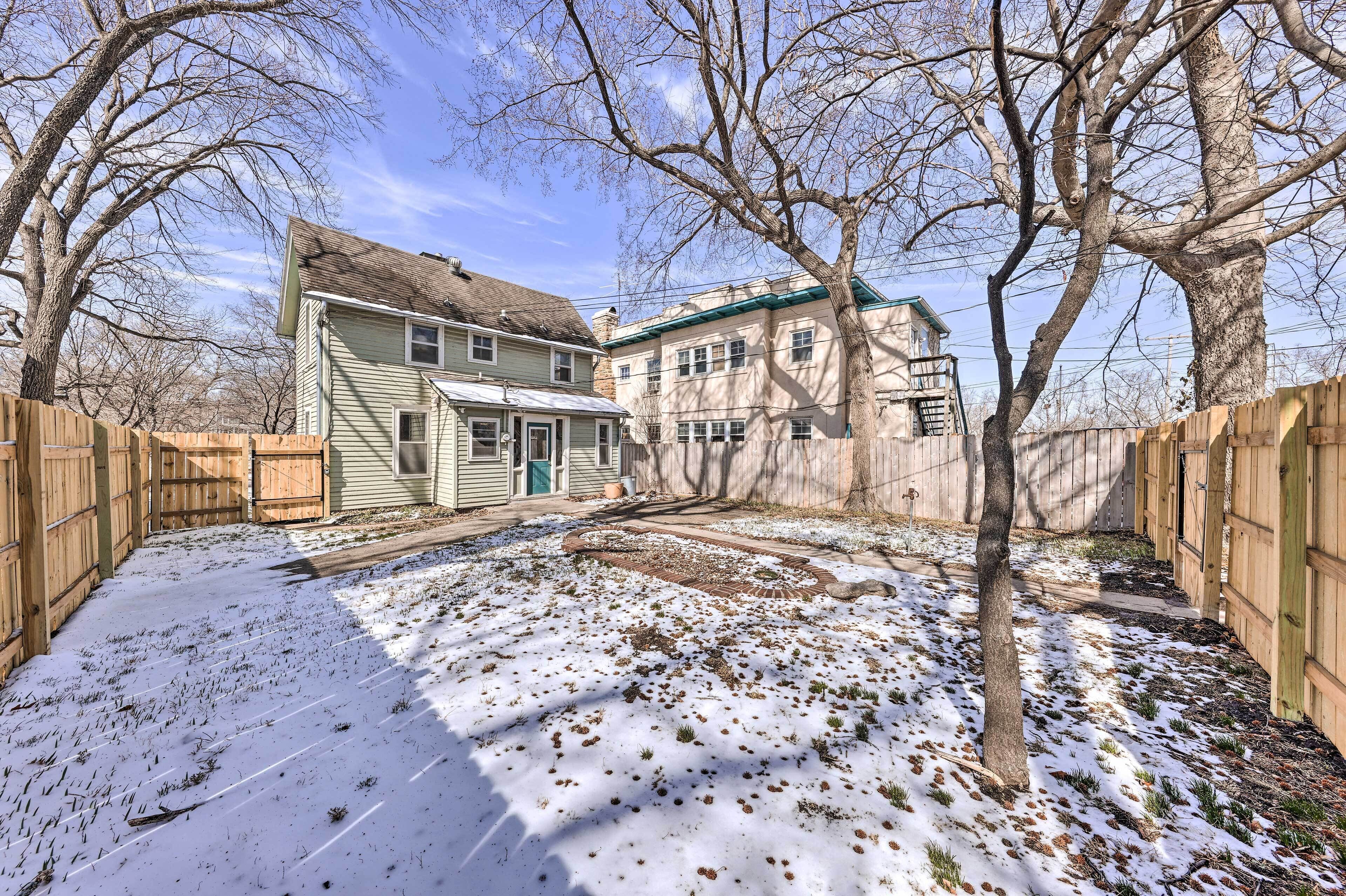 Une maison à deux étages avec un jardin devant et une clôture en bois.