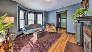 A living room with a blue sofa, a patterned rug, a wooden floor, and a fireplace. - Newly Renovated Home Close to Dtwn Lawrence! (Lawrence)