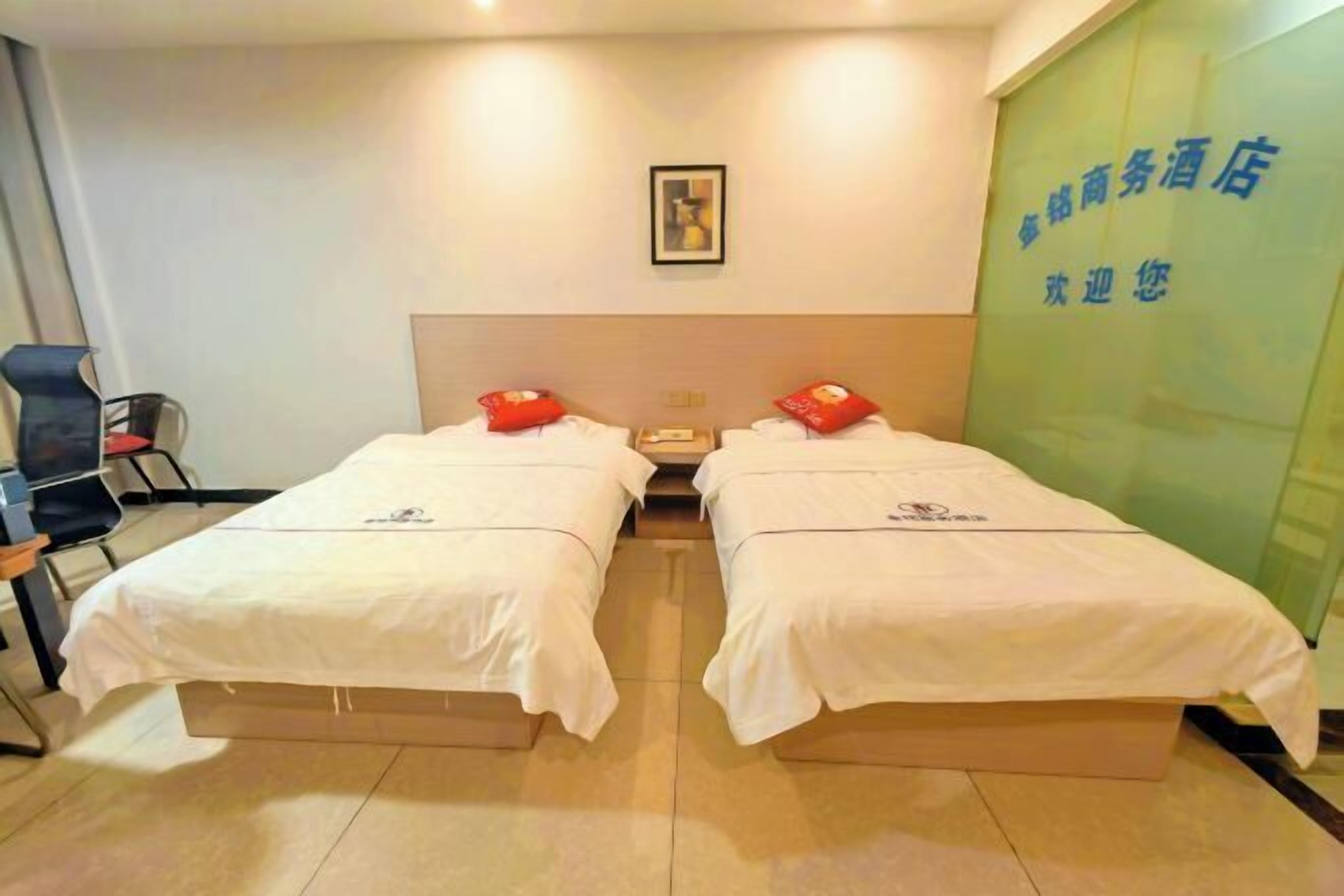 A hotel room with two beds, a chair, and a green wall with text.