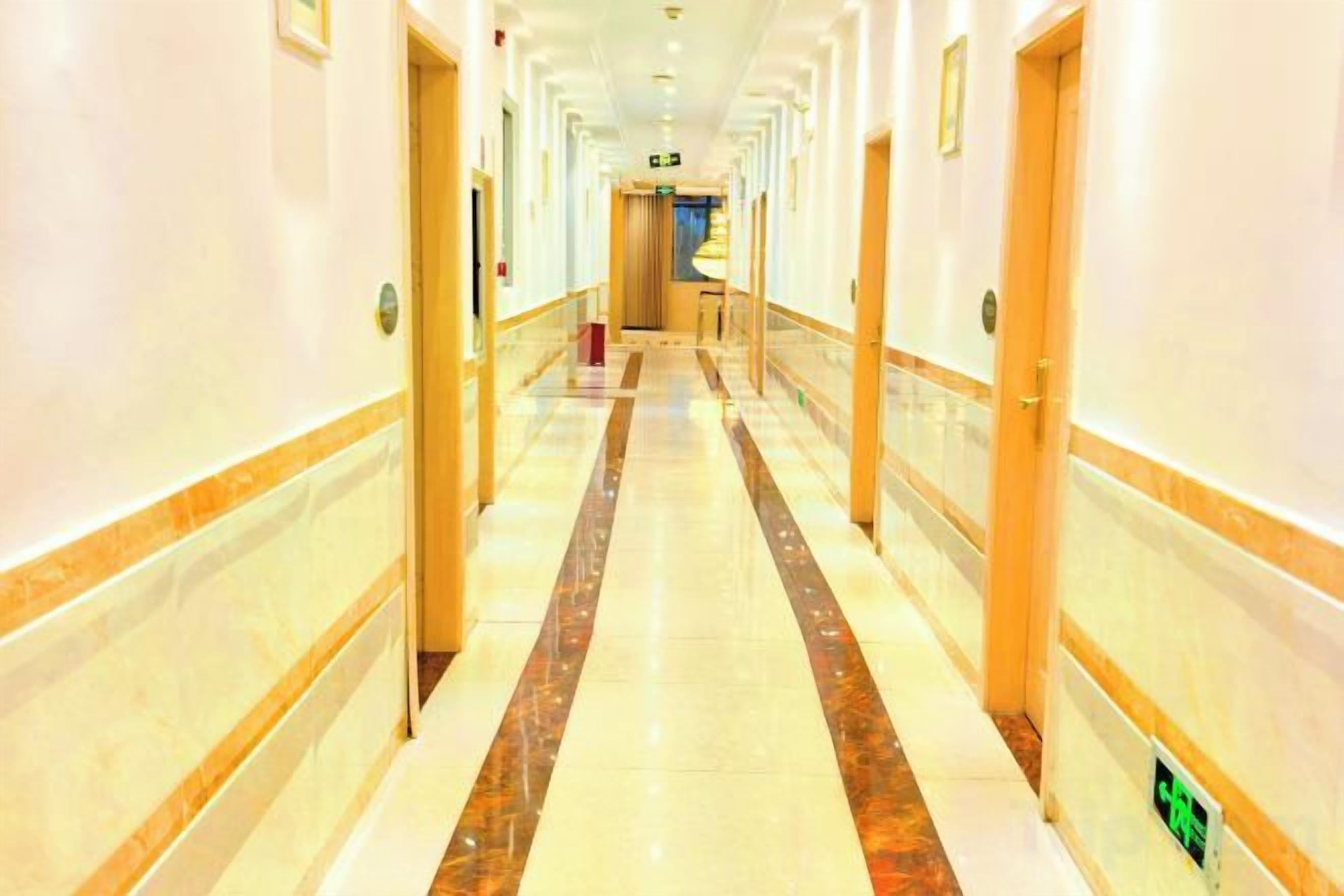 Un pasillo de hotel con puertas a ambos lados, piso de mármol y pared de color claro.
