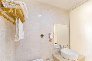 A bathroom with a marble wall, a sink, a mirror, and a towel rack with towels. - jinmingHOTEL (Shangrao)