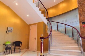 Eine Hotelhalle mit Treppe, einer Rezeption und einer Tür.