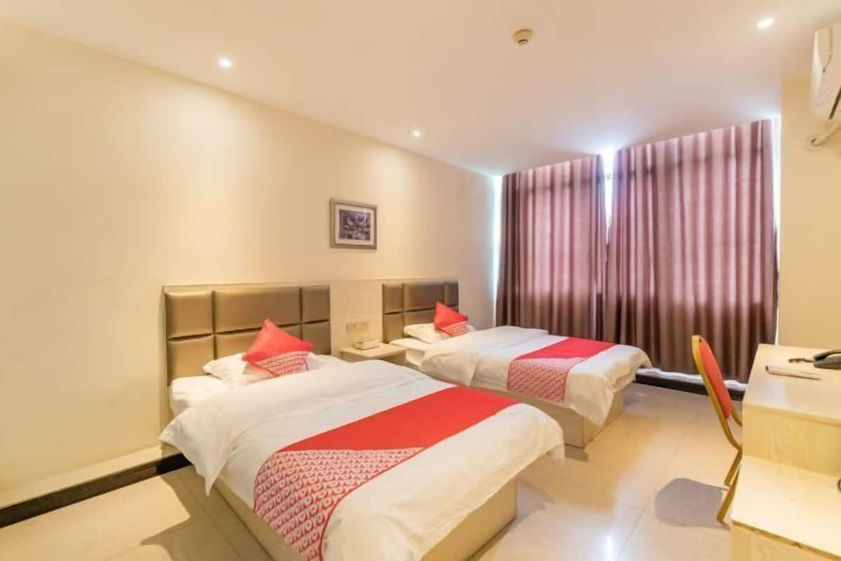 Hotellihuone, jossa on kaksi sänkyä, työpöytä ja tuoli.