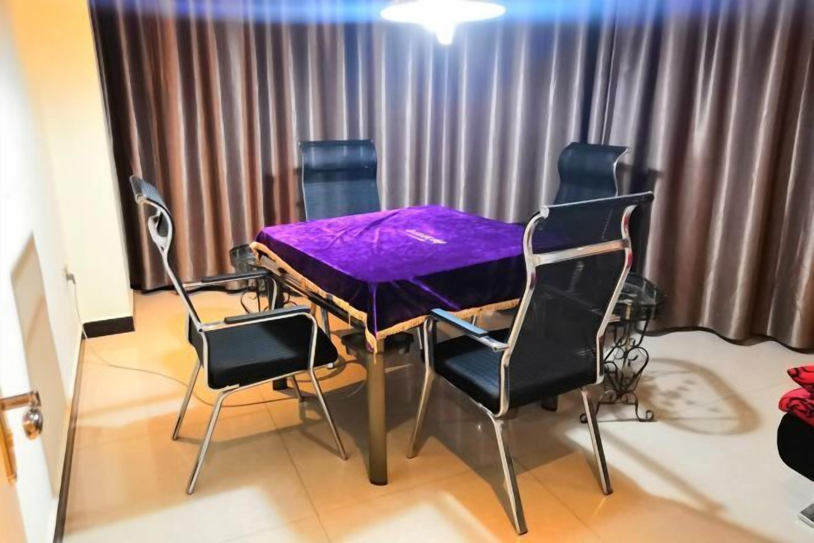A dining area with a table covered in purple, four chairs, and a curtain backdrop.
