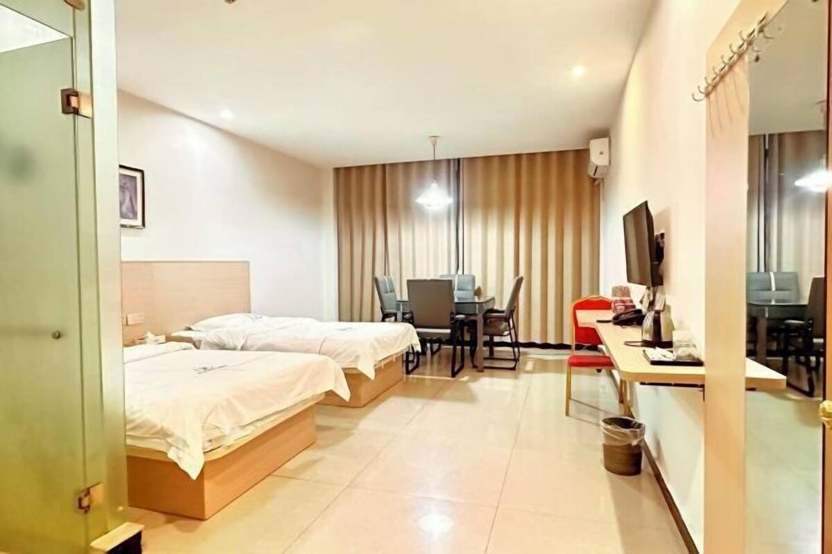 Hotellihuone, jossa on kaksi sänkyä, työpöytä ja tuoli.
