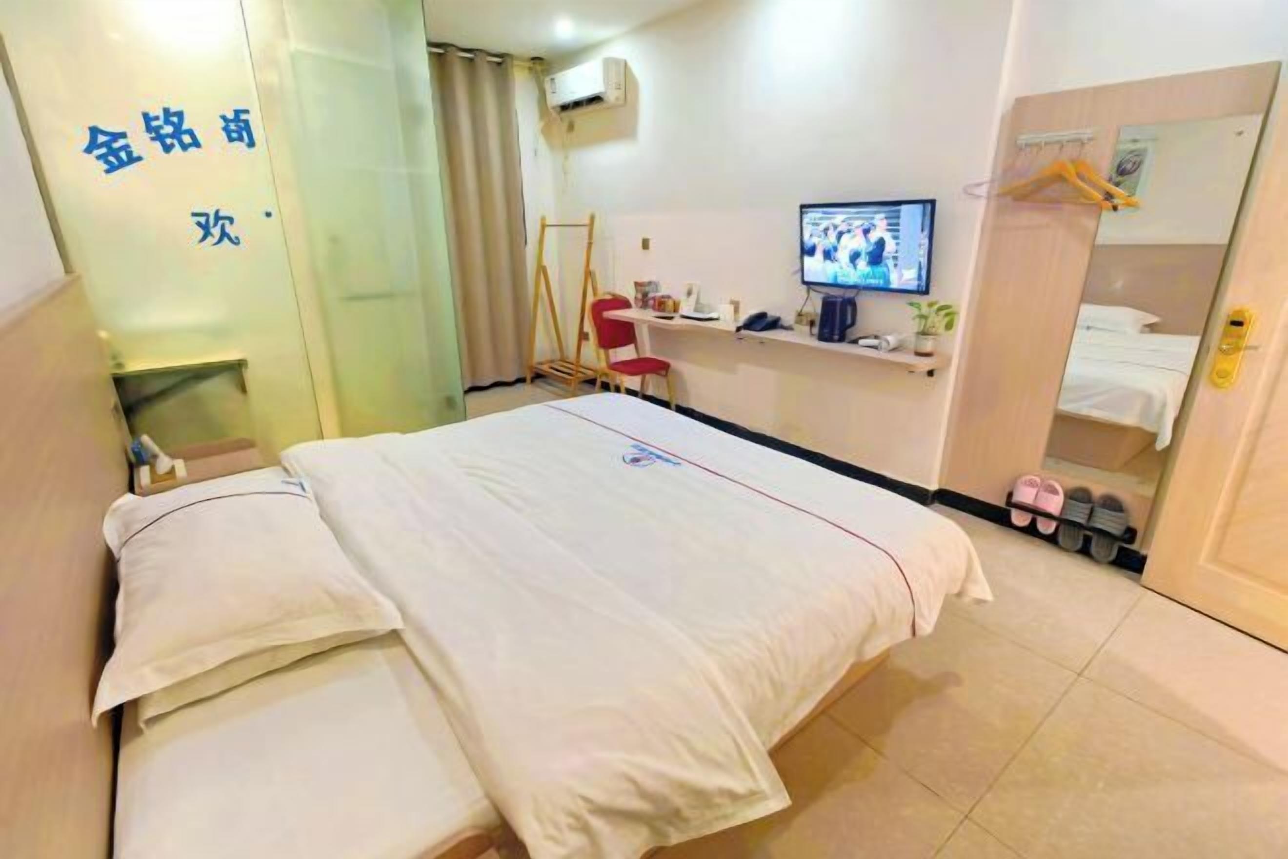 Une chambre d’hôtel comprenant un lit, un bureau avec un ordinateur, une télévision et une armoire.