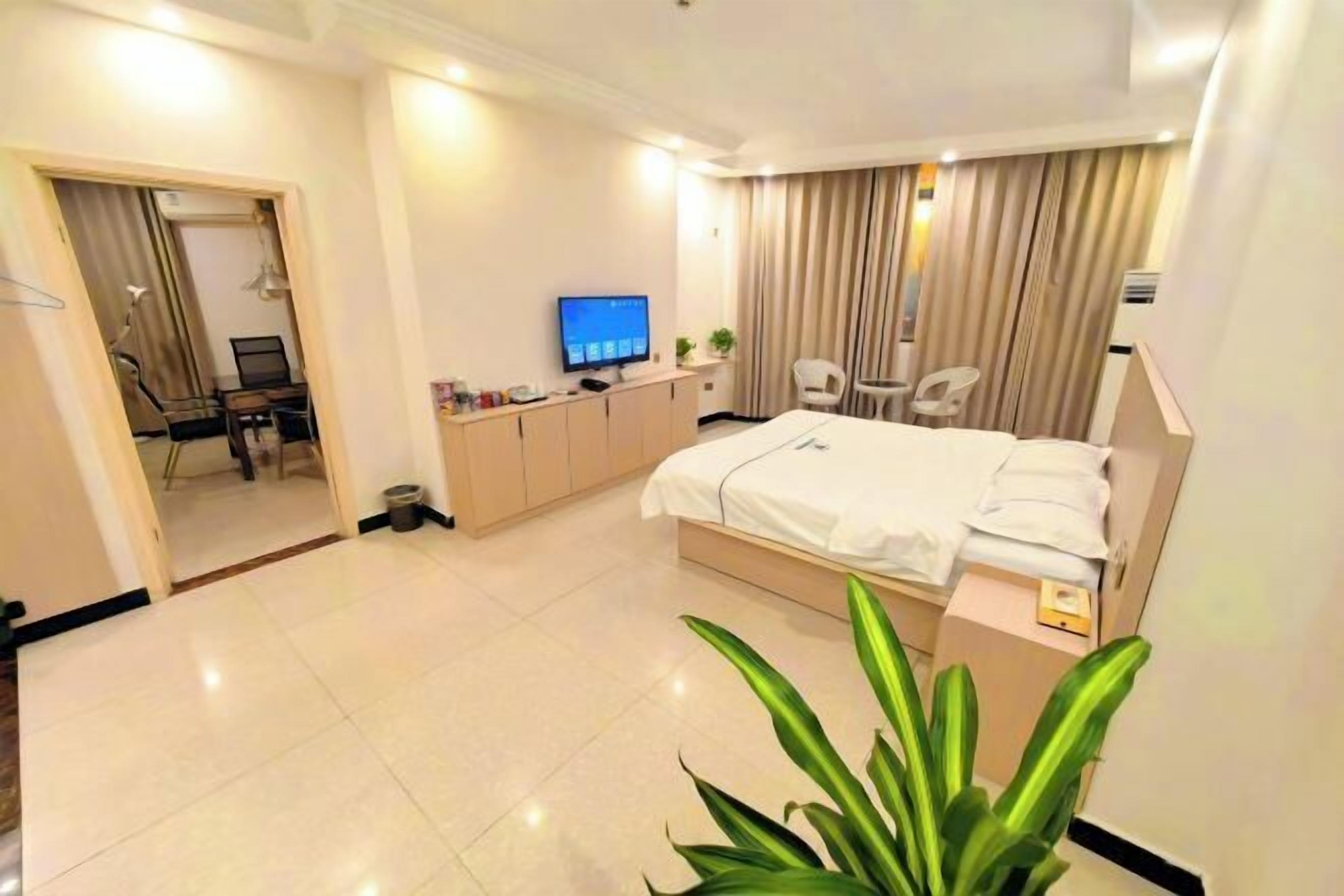 A modern hotel room with a large bed, a desk with a computer, a television, and a chair.