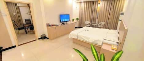 A modern hotel room with a large bed, a desk with a computer, a television, and a chair.
