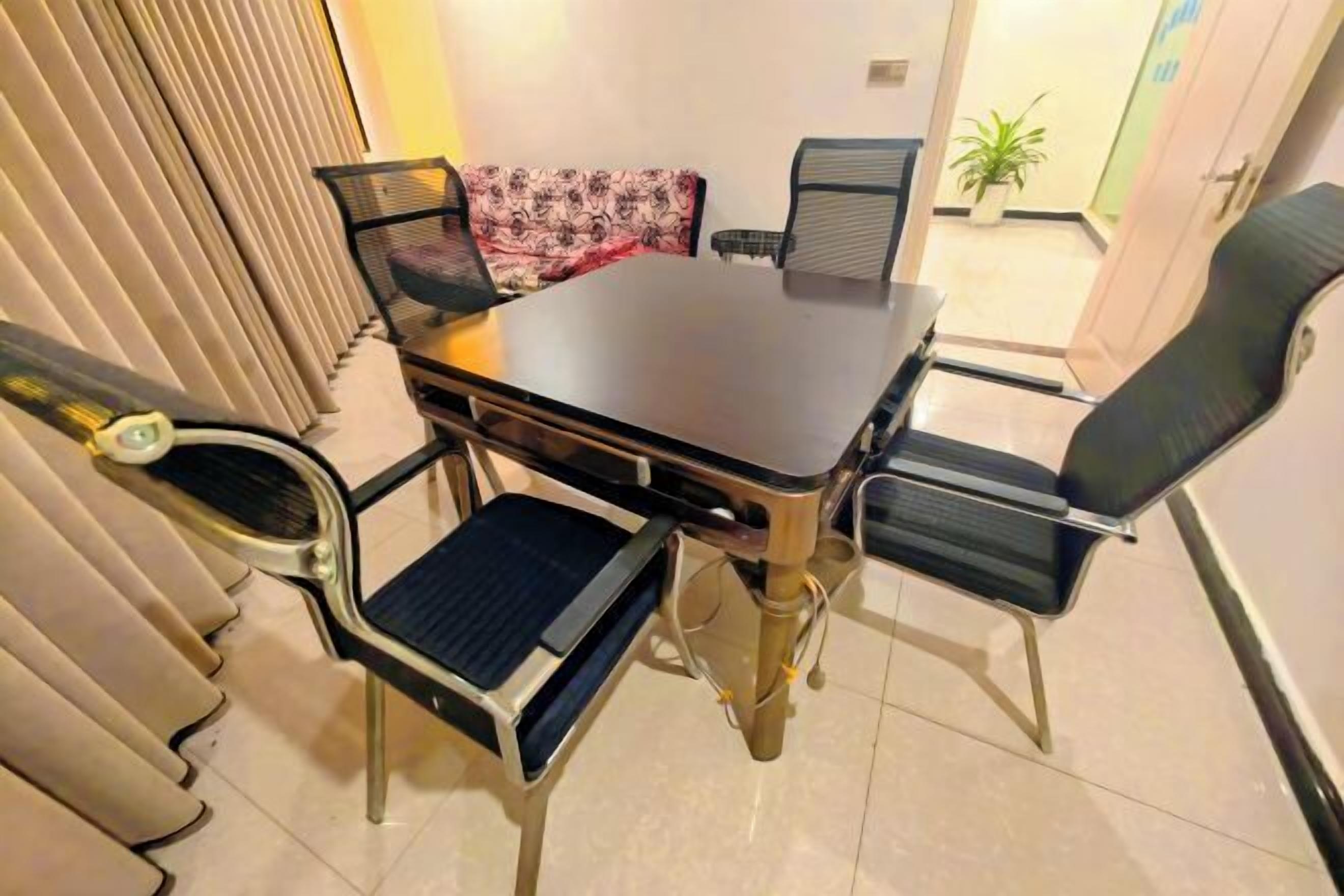A dining area with a rectangular table and four chairs, a sofa, and a small side table.