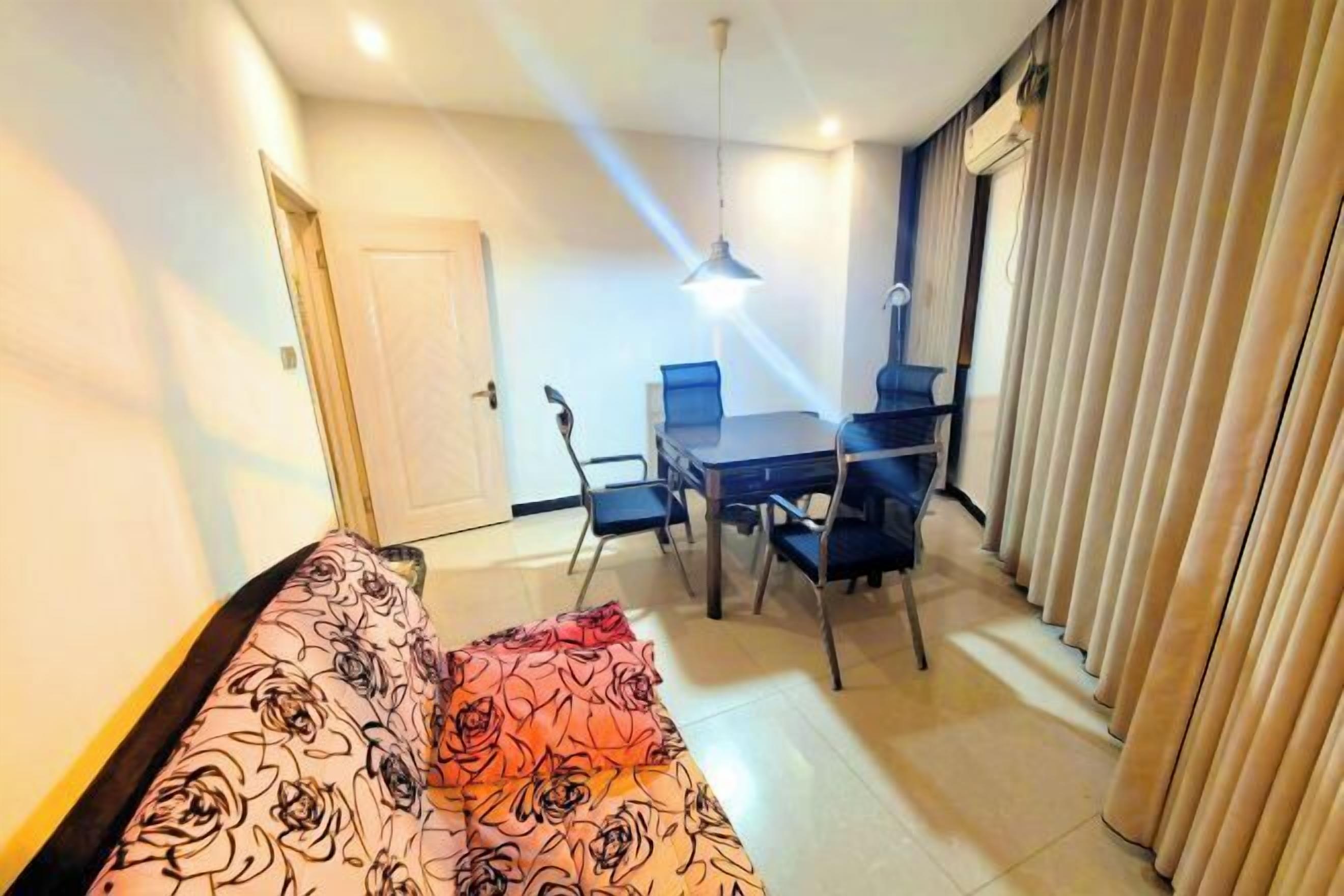 A living room with a sofa, a dining table with chairs, a ceiling light, and a door.