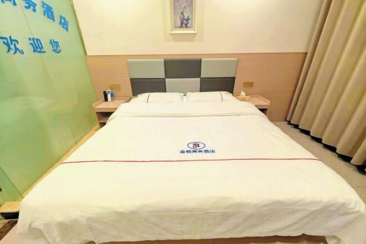 Une chambre d’hôtel avec un lit, une table de chevet, une horloge murale et un rideau.