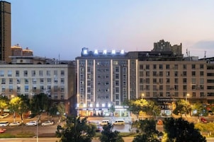 A multi-story hotel with a central atrium, surrounded by other buildings, and a busy street in the foreground.