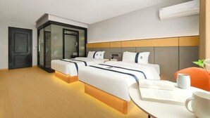 Una camera d'albergo con due letti, una scrivania, una sedia e un condizionatore.